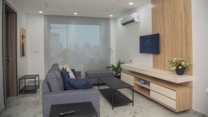 A modern living room with a sofa, a coffee table, a TV mounted on a wooden wall, and a potted plant. - MiVi (Lagos)