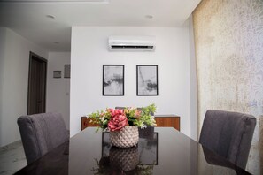 A conference room with a dark wooden table, two gray chairs, a vase with flowers, and two framed pictures on the wall. - MiVi (Lagos)