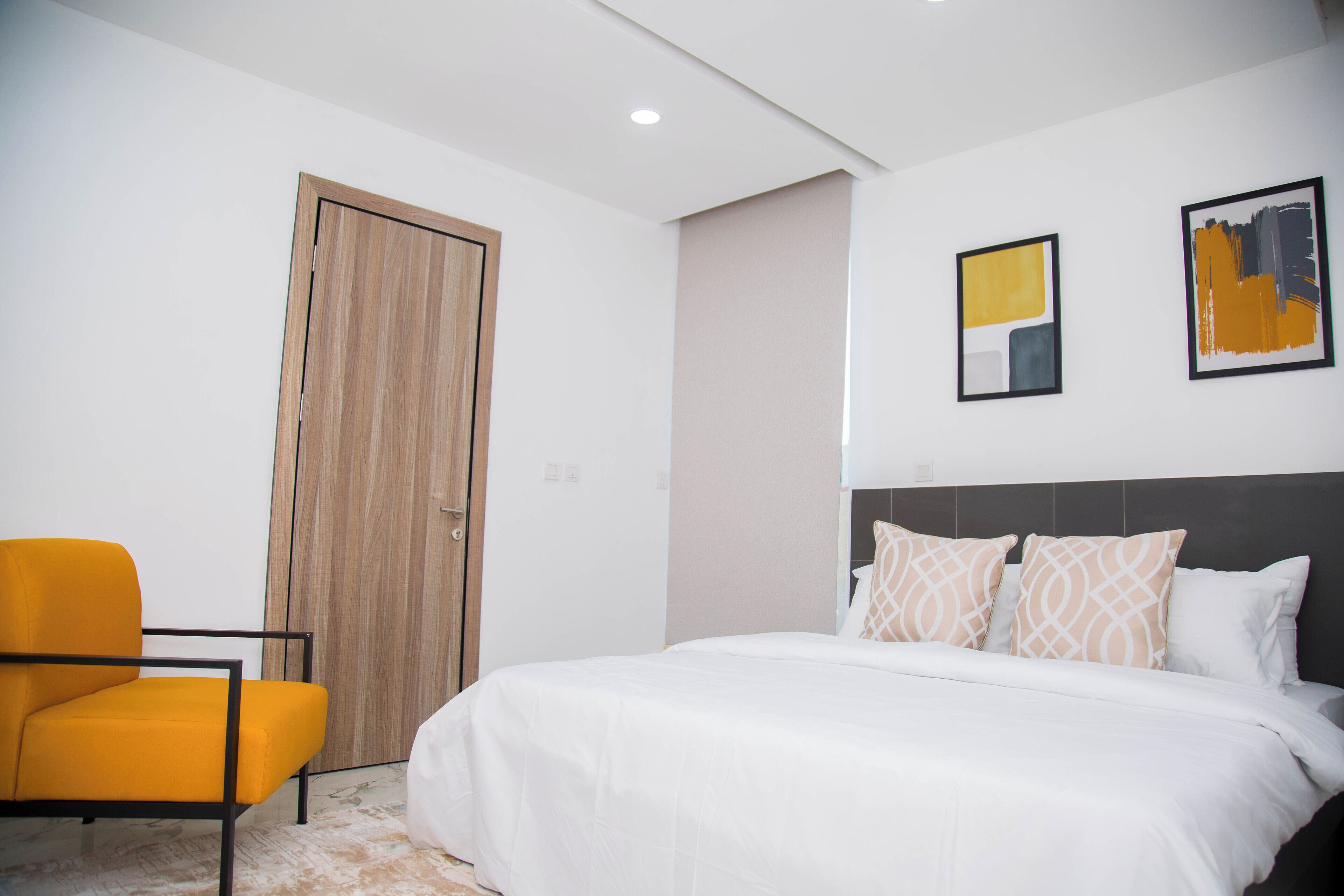 A modern hotel room with a bed, a chair, and artwork on the wall.