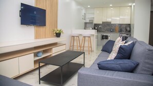 A modern living room with a grey sofa, a black coffee table, and a TV mounted on the wall. - MiVi (Lagos)