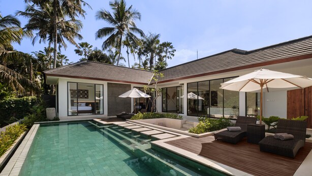 A modern pool area with a clear pool, wooden deck, and lounge chairs. - Villa Jenggala by GORO (Ubud)
