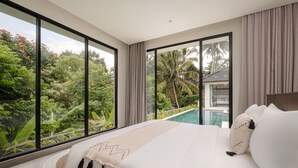 A bedroom with a large bed, a view of a swimming pool, and lush greenery outside. - Villa Jenggala by GORO (Ubud)