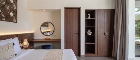 A modern hotel room with a large bed, a wooden wardrobe, a desk with a lamp, and a large window with curtains.