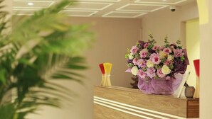 Een receptiebalie met bloemen, een plant en een vloer met patroon.