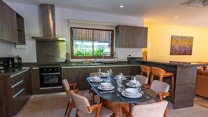 A modern kitchen with a central island, built-in oven, and stainless steel range hood. - Tranquil Escape: Private 4BR Pool Villa with Garden (Rawai)