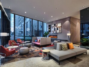 Un vestíbulo moderno con un amplio espacio de estar, chimenea y ventanas grandes con vistas a la ciudad.