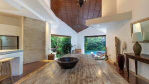 A spacious room with a large wooden table, a ceiling fan, and a view of a pool.