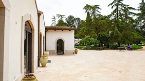 A courtyard with a building entrance, large vases, and outdoor seating. - Wine & Resort Le Vigne al Castello (Andria)