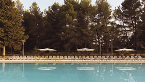 A swimming pool with lounge chairs and umbrellas, surrounded by trees. - Wine & Resort Le Vigne al Castello (Andria)