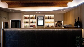 A bar area with shelves of liquor bottles, a refrigerator, and a wooden ceiling. - Wine & Resort Le Vigne al Castello (Andria)
