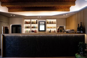 Una zona de bar con estantes llenos de botellas de licor, un refrigerador y un techo de madera.