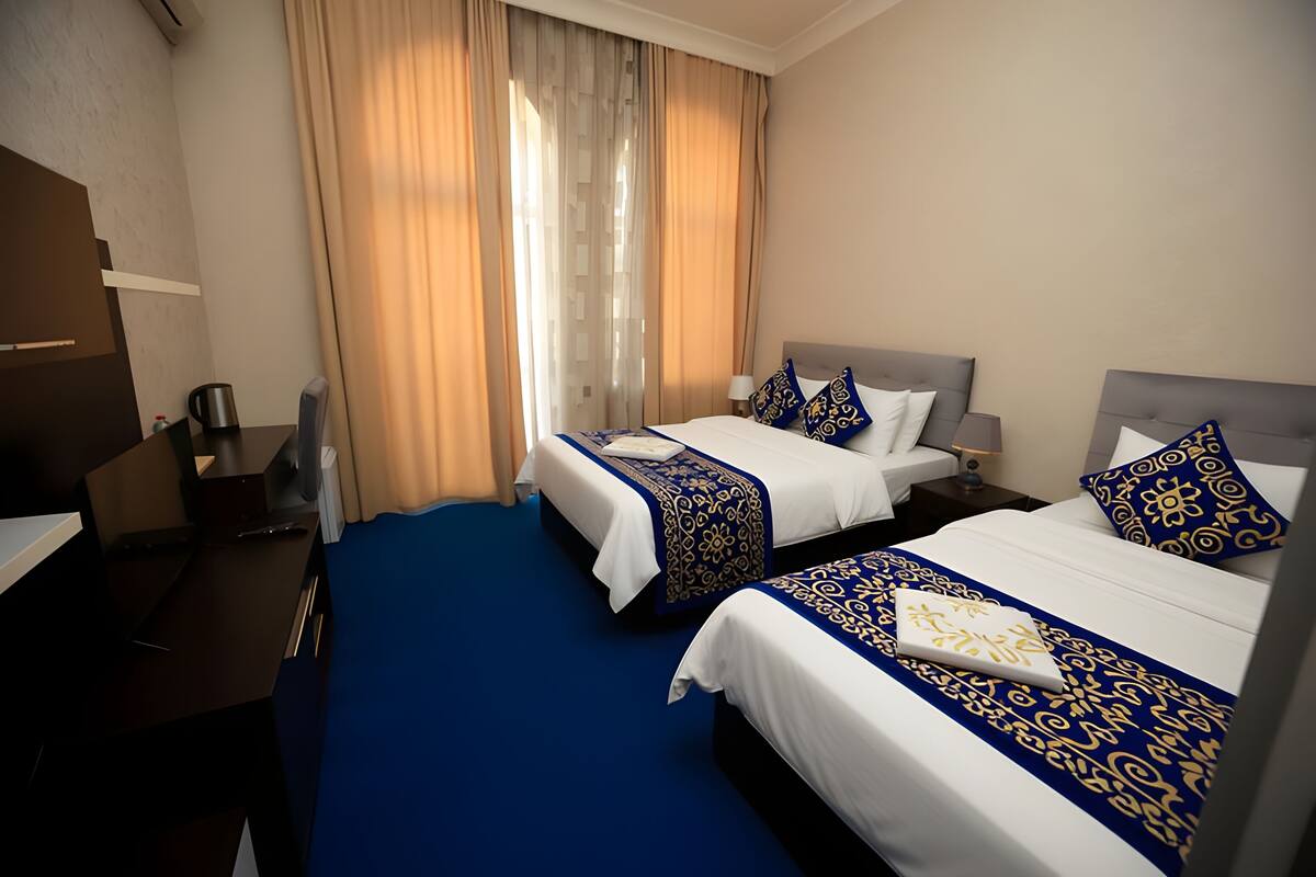 Habitación de hotel con dos camas, un escritorio y una silla.