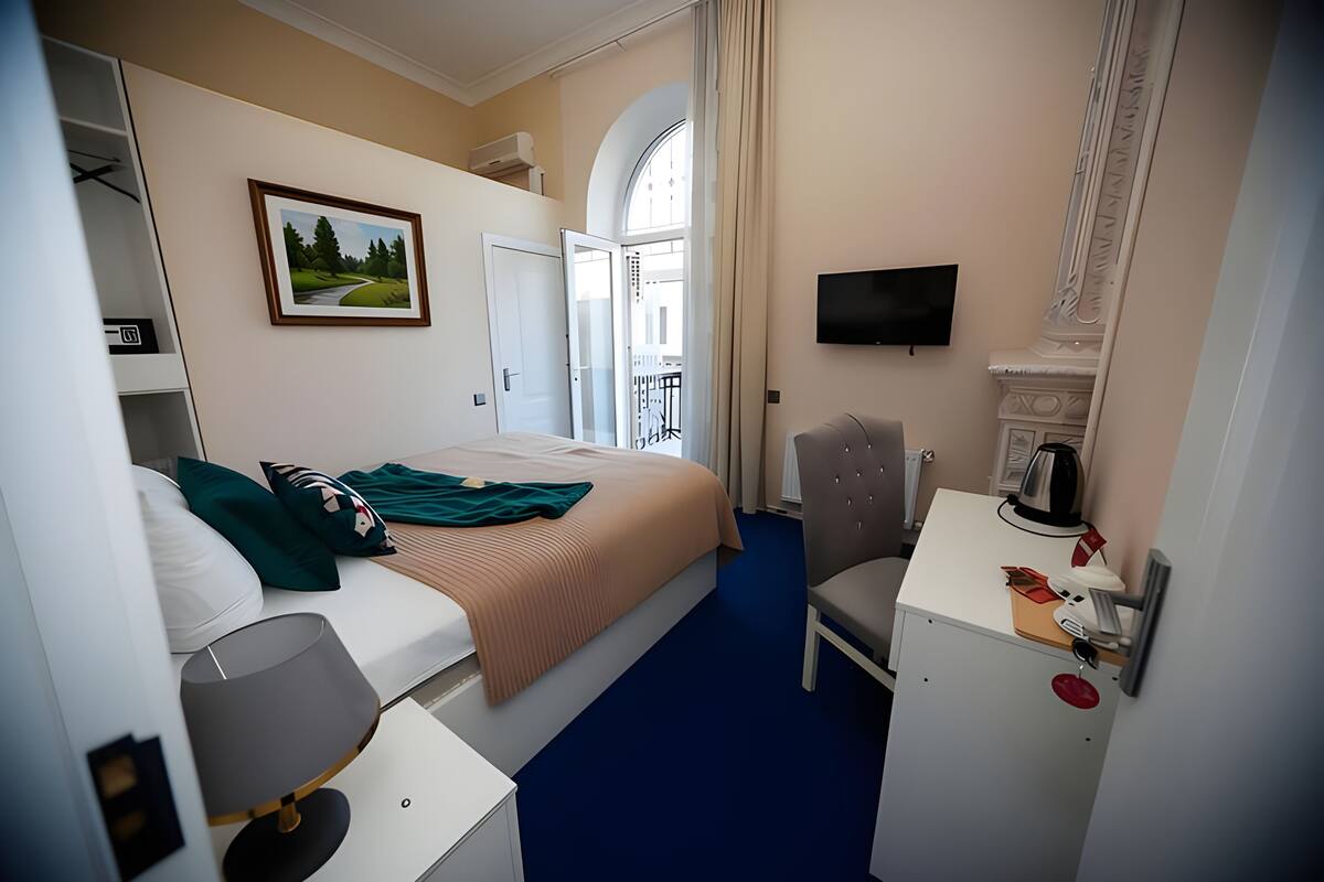 Habitación de hotel con cama, escritorio, silla, televisor y un cuadro en la pared.