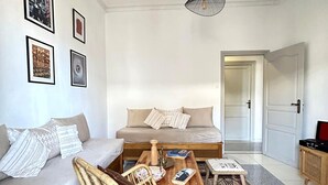 A cozy room with a sofa, a wooden coffee table, a wicker chair, and a patterned rug.