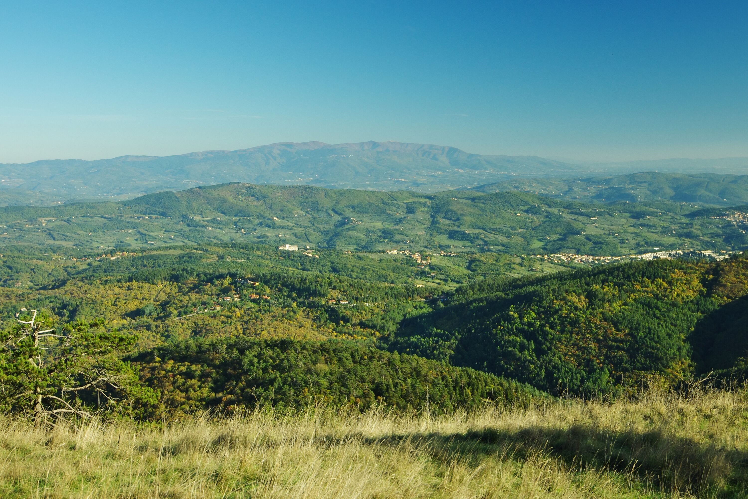 Ein Panoramablick auf eine gebirgige Landschaft, mit einem Dorf, das im Tal liegt.