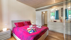 A bedroom with a large bed, a bedside table, a dresser, and a mirror. - Trekking Home La Via degli Dei Toscana (Vaglia)