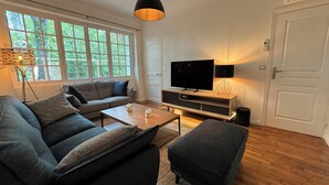 Ein modernes Wohnzimmer mit einem grauen Sofa, einem Couchtisch und einem Fernseher auf einer Holzkommode.