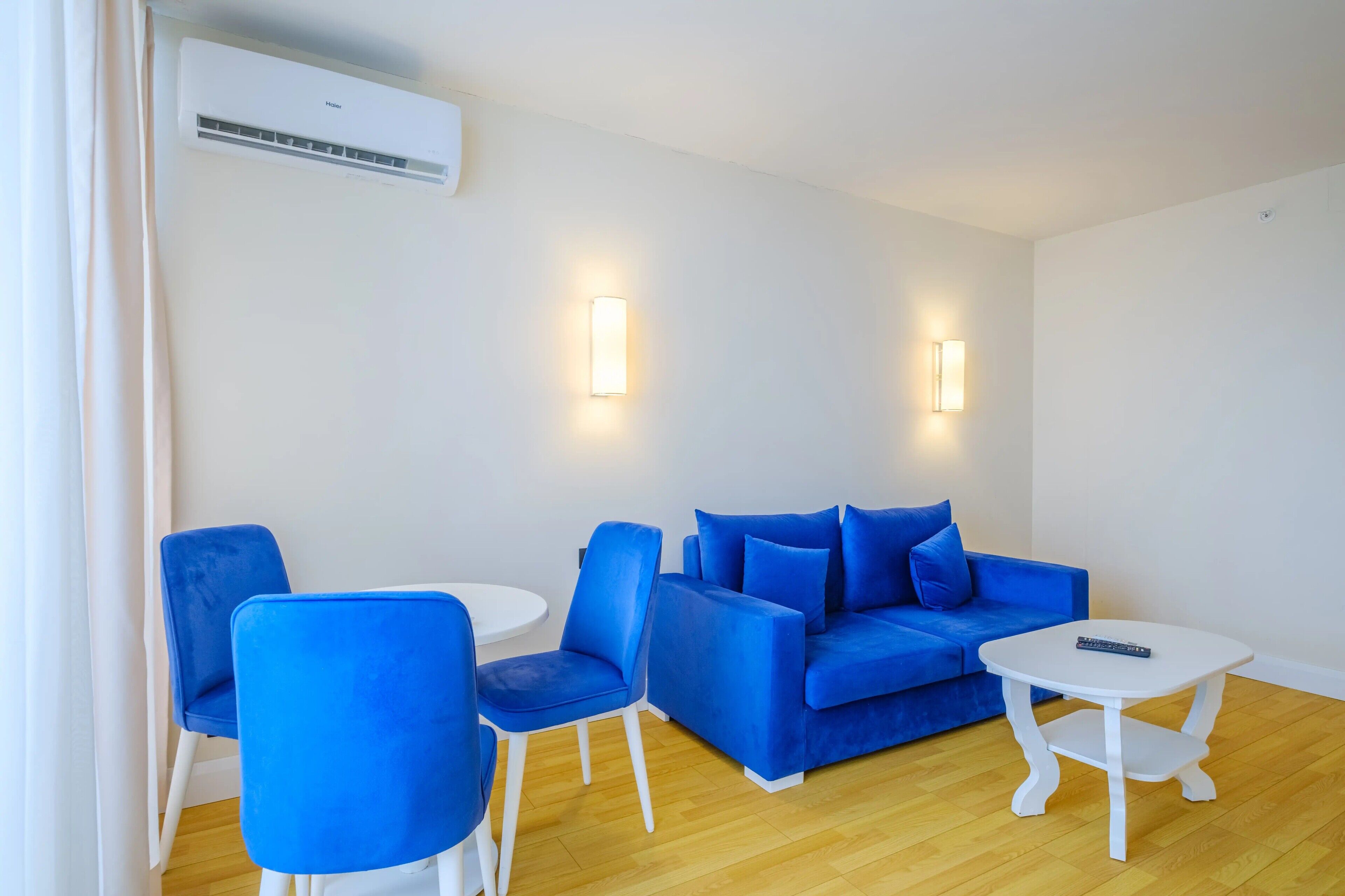 Un salon moderne avec un canapé bleu, des fauteuils assortis et une table basse blanche.
