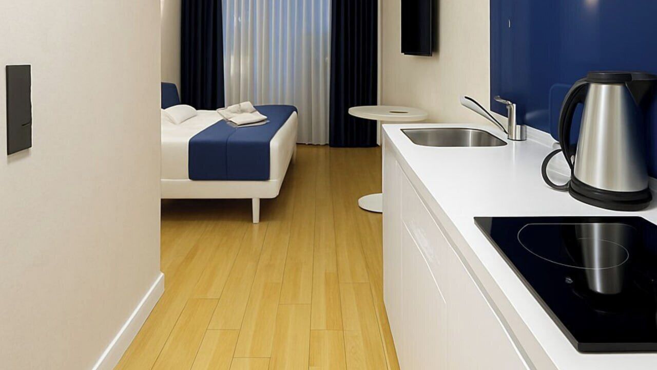 Una habitación de hotel moderna con una cama, una kitchenette pequeña y un lavamanos.