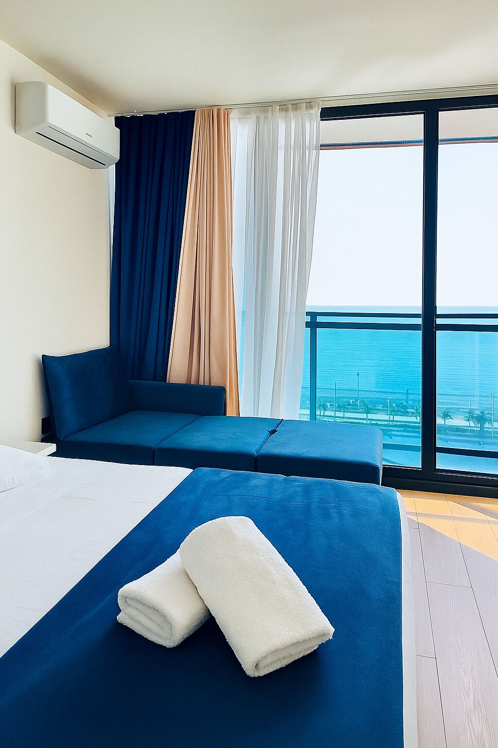 Une chambre d’hôtel moderne avec un grand lit, un canapé et une vue sur l’océan.
