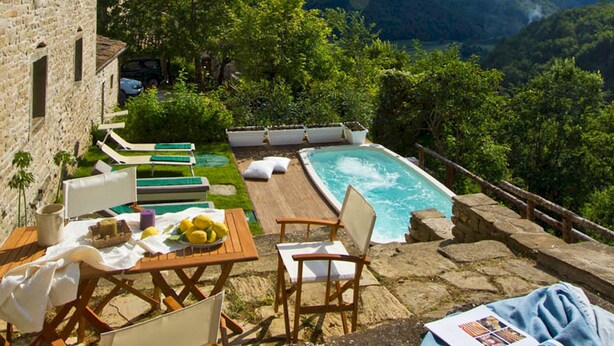 A stone building with a pool and outdoor seating area overlooking a mountainous landscape. - Casa del Mandorlo 8 Emma Villas (Mercatello sul Metauro)