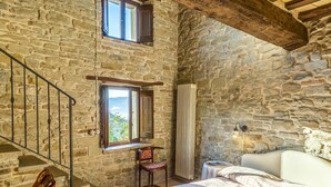 A rustic stone-walled bedroom with a bed, a chair, a table, and a window. - Casa del Mandorlo 8 Emma Villas (Mercatello sul Metauro)