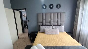 Ein Schlafzimmer mit einem großen Bett, einem Kopfteil und einem Nachttisch.