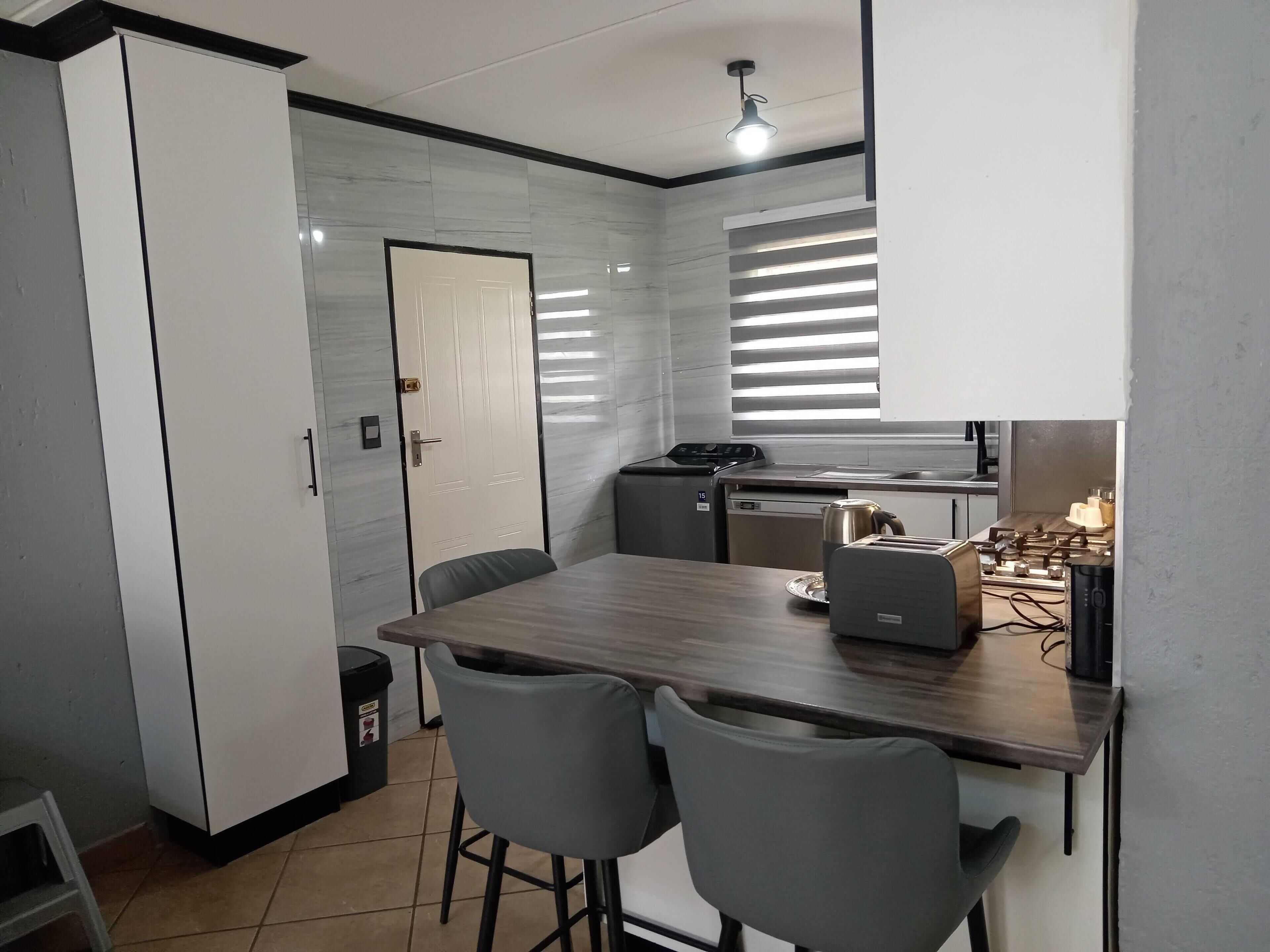 A compact kitchen with a built-in stove, a sink, and a small dining area with two chairs.