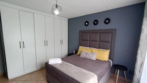 A bedroom with a large bed, a wardrobe, and a ceiling light fixture.