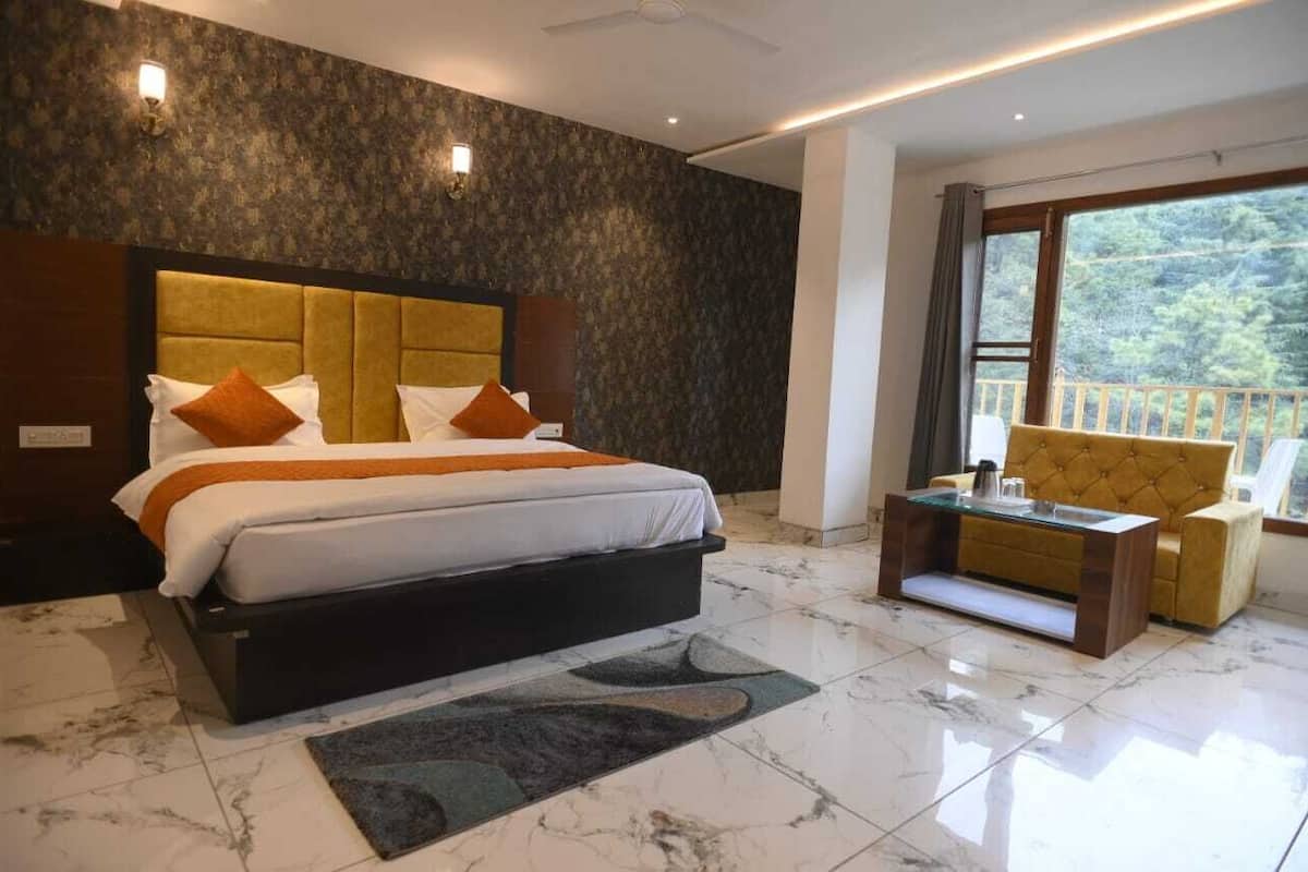 A bedroom with a large bed, a sofa, and a view of the outdoors.