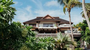 A two-story house with a stone facade, wooden balcony railings, and a sloped roof. - Villa Zebra Moon by muse villas (Cap Malheureux)