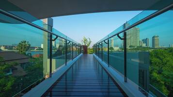 Eine moderne Glasbrücke mit freiem Blick auf die Stadtlandschaft und die darunterliegende Grünfläche.