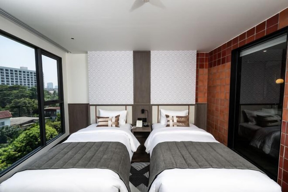 Ett hotellrum med två sängar, ett stort fönster och utsikt över staden.