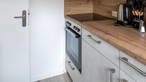 A modern kitchen with a wooden countertop, stainless steel appliances, and light grey cabinetry. - Apartment Meeresbrise, Modern & Liebevoll Eingerichtet, Wlan, Smart TV (Wilhelmshaven)