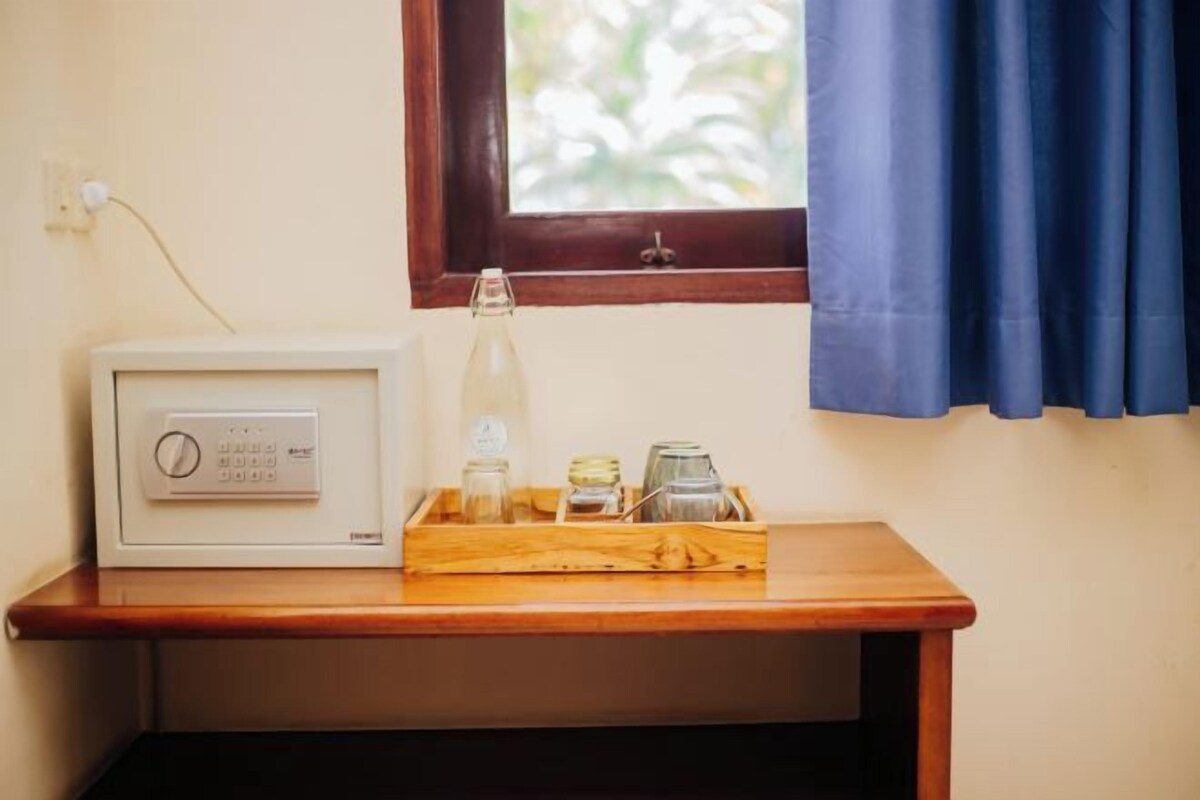 A room with a wooden table, a white thermostat, a bottle, and jars.