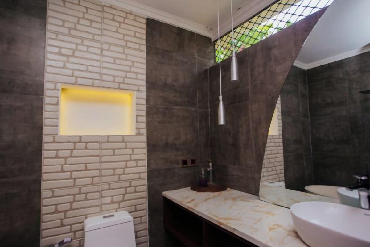 A modern bathroom with a marble vanity, a large mirror, and a unique brick wall design.