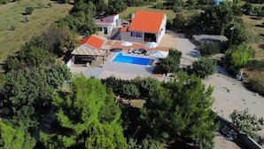 Une grande maison avec une piscine, entourée d’arbres et d’un jardin.