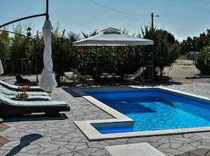 A swimming pool with lounge chairs and a covered seating area.