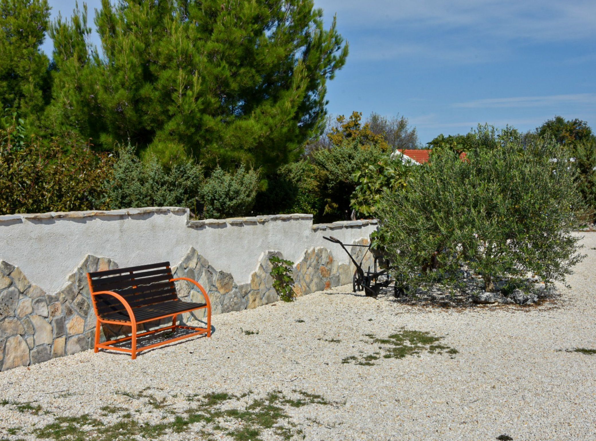 A bench with a stone wall and trees in the background.