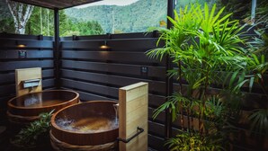 Een houten sauna met twee grote houten kuipen, een houten bank en een potplant.