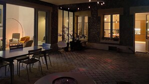Un espacio al aire libre con patio, una mesa de comedor, sillas y un hogar para fuego.