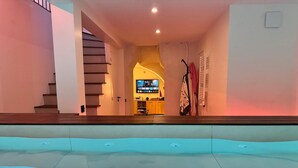 Una piscina con vistas a una escalera que lleva a una sala de estar con televisión.