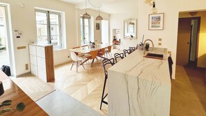 Una cocina amplia con una isla de mármol, armarios de madera y un comedor con una mesa grande y sillas.