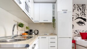 Una cocina moderna con armarios blancos, un lavamanos de acero inoxidable y una cafetera.