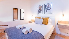 A modern hotel room with a large bed, two bedside tables, a wooden nightstand, and artwork on the walls. - Villa Burgães (Porto)