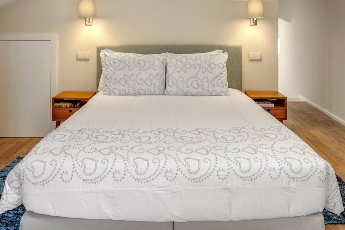 Une chambre à coucher comprenant un lit, deux tables de chevet et deux lampes fixées au mur.