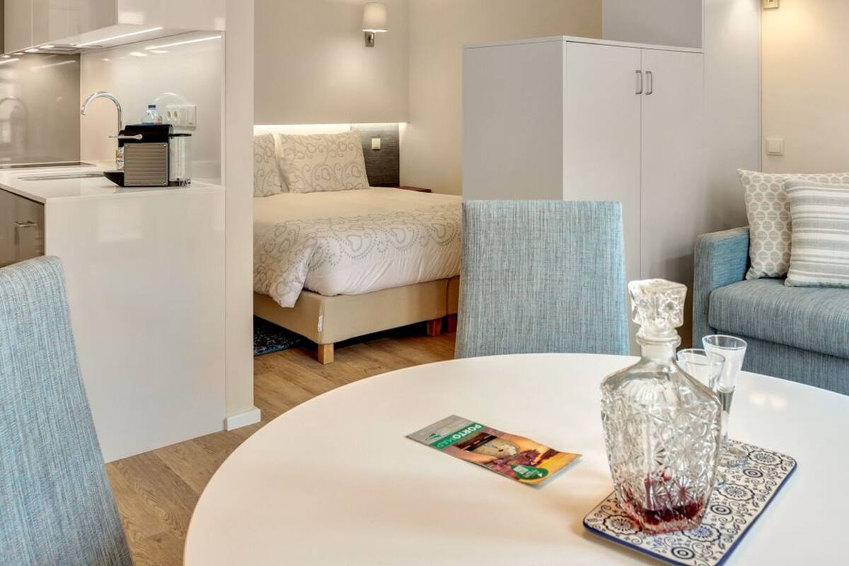 Une chambre d’hôtel compacte comprenant un lit, un canapé, une table à manger, un coin cuisine et une armoire.