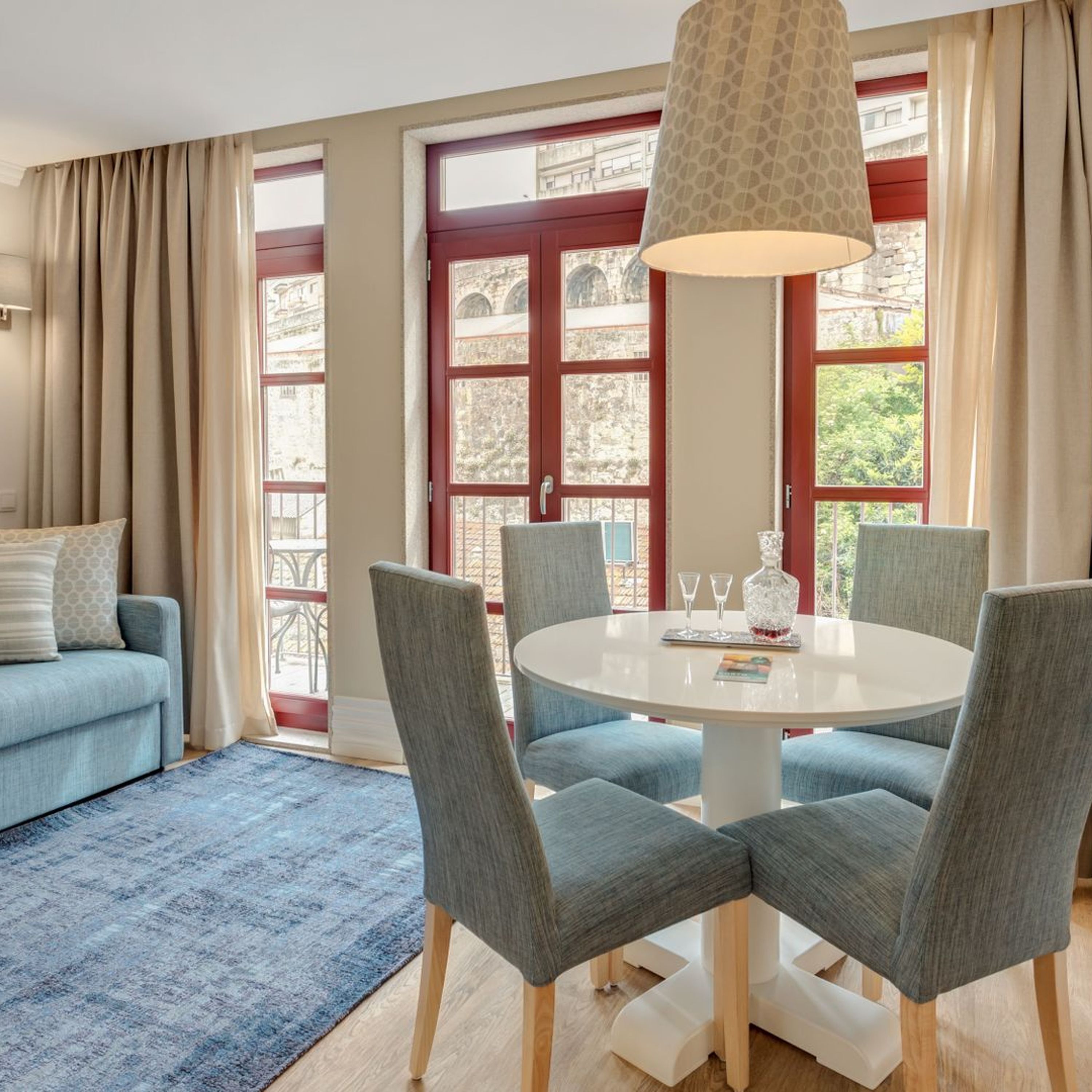 A dining area with a round table, four chairs, and a hanging light fixture.