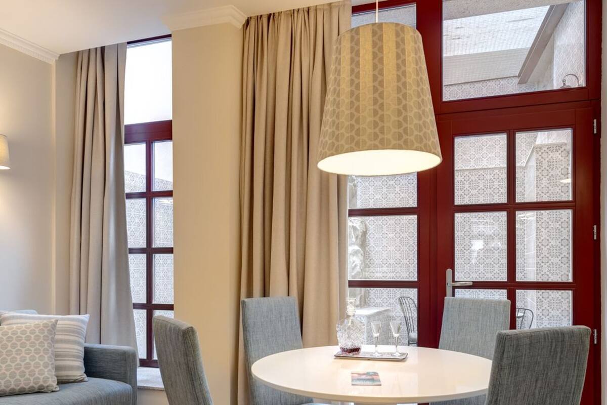 Un salon moderne avec une table ronde, des fauteuils à revêtement gris, un canapé gris et un lampadaire au plafond à motifs.
