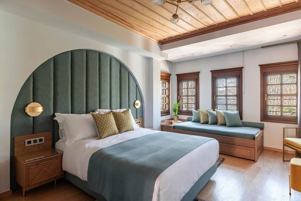Un dormitorio con una cama grande, una banca y un escritorio.